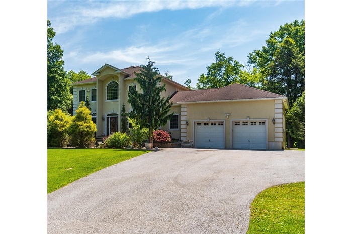View of front of house featuring driveway, an attached garage, a front lawn, and stucco siding