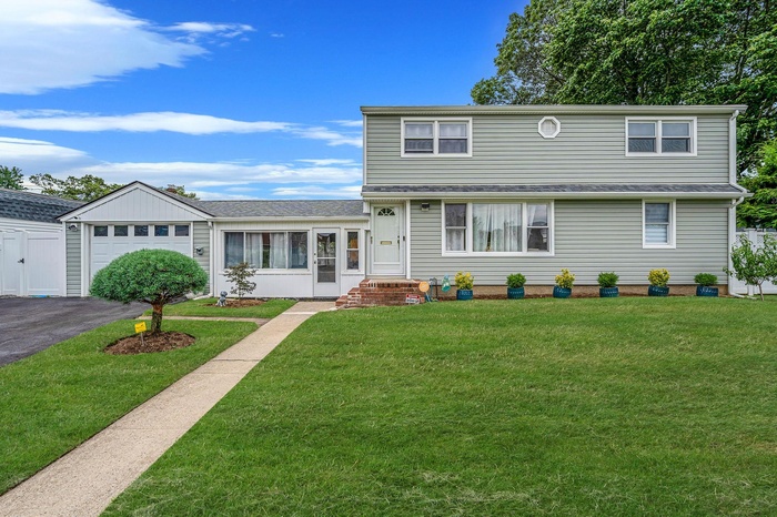 Colonial home featuring a breezeway with attached garage and asphalt driveway