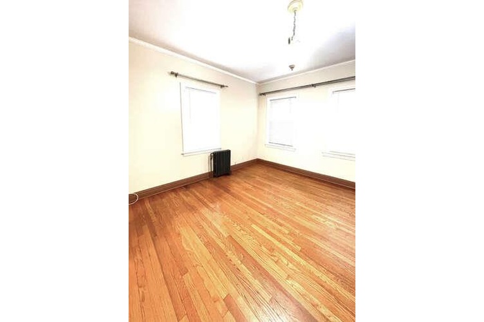 Spare room with ornamental molding, light wood-type flooring, and radiator heating unit