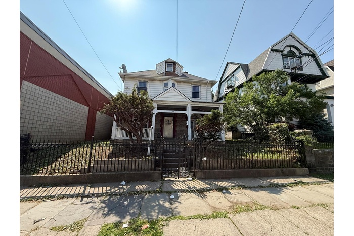 American foursquare style home featuring covered porch, a fenced front yard, and a gate