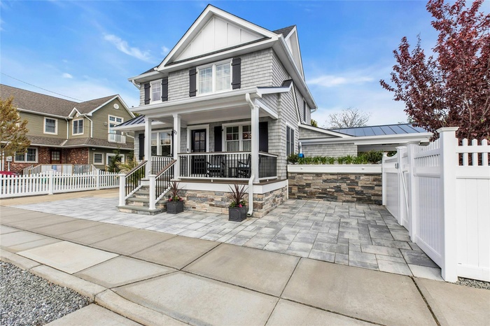 View of front of home with covered porch, a gate, fence, board and batten siding, and a standing seam roof