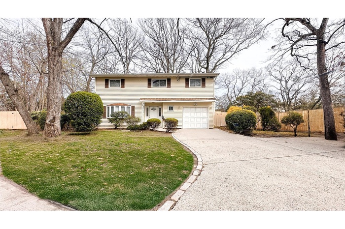 Traditional-style house with a front lawn, fence, a garage, and driveway