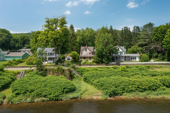 View from above of property with a nearby body of water and a heavily wooded area