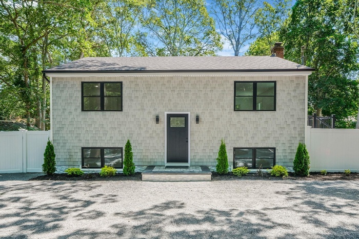 View of front facade featuring a shingled roof and a chimney