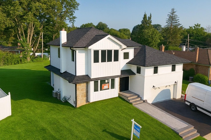 Modern farmhouse style home with a shingled roof, board and batten siding, an attached garage, asphalt driveway, and a front yard