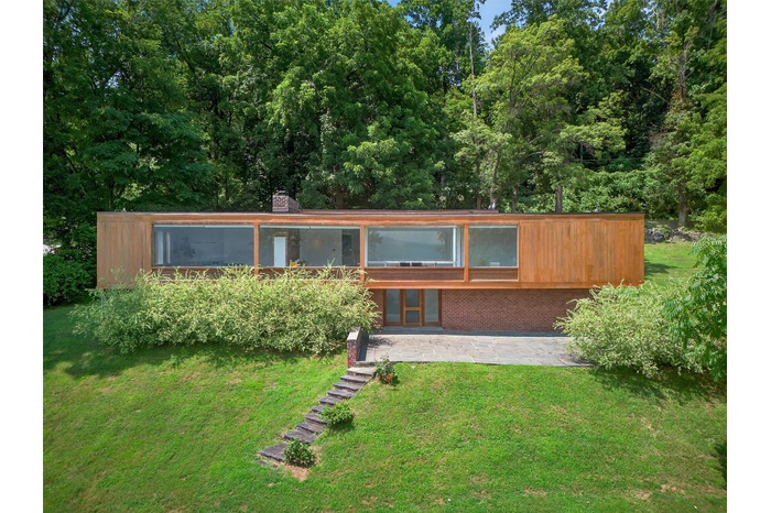 View of front of house with a front lawn, a patio area, brick siding, and a chimney