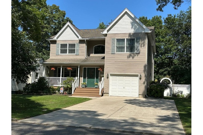 View of front of property with covered porch, an attached garage, and concrete driveway