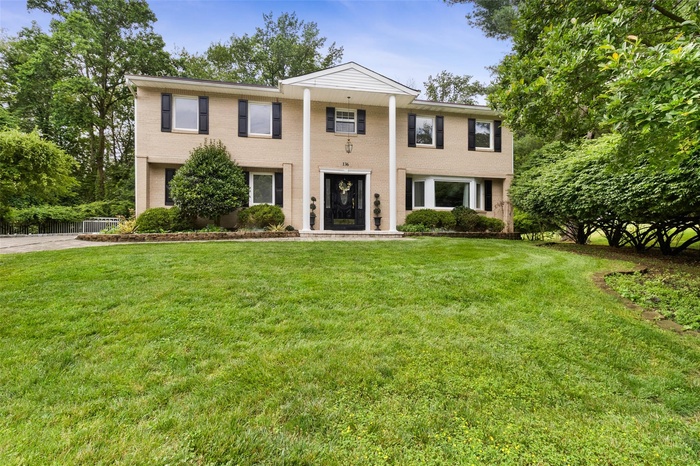 Neoclassical / greek revival house featuring brick siding and a front lawn