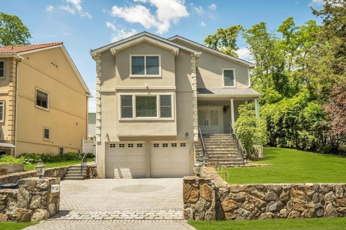 View of front of house featuring stucco siding, decorative driveway, an attached garage, a front yard, and stairs