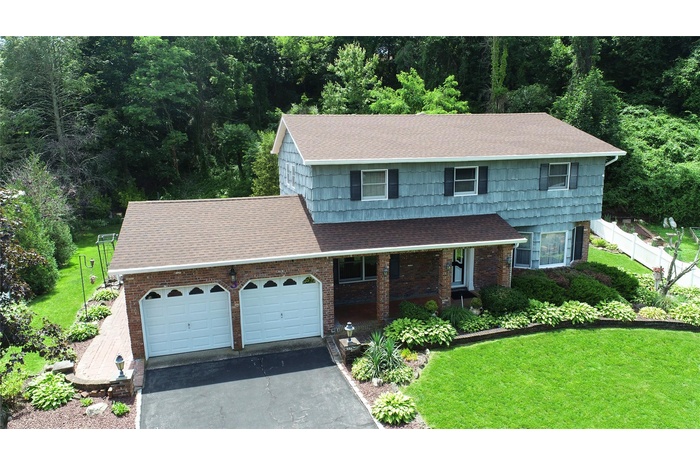 View of front of home with roof with shingles, asphalt driveway, an attached garage, covered porch, and brick siding