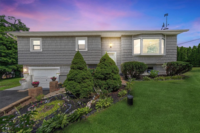 Raised ranch with a front yard, a garage, and driveway