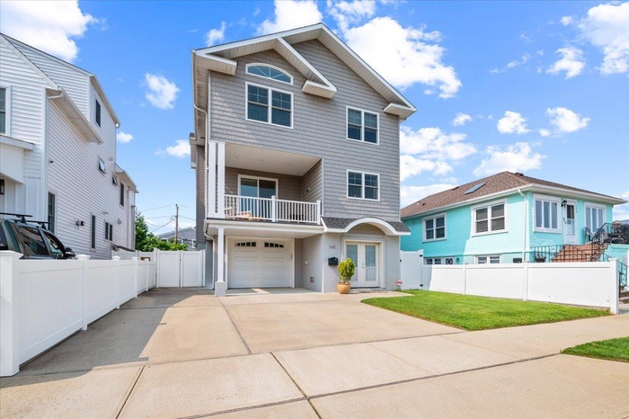 View of front of house with a balcony, driveway, a garage, and french doors