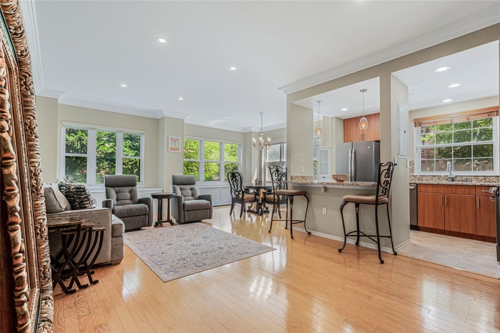 Living room featuring a chandelier, ornamental molding, light wood-style flooring, and recessed lighting