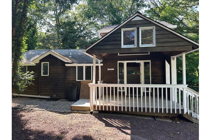 View of house featuring covered porch and roof with shingles