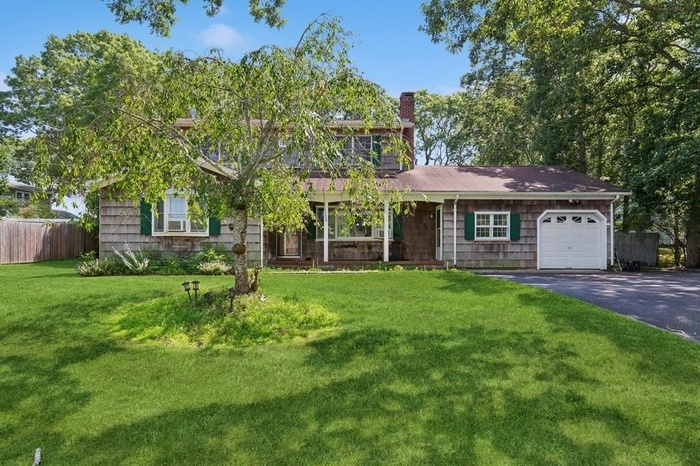 View of front of home featuring asphalt driveway, an attached garage, and a chimney