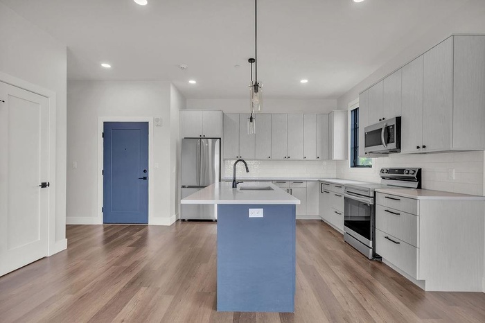 Kitchen with stainless steel appliances, an island with sink, light wood finished floors, decorative backsplash, and recessed lighting