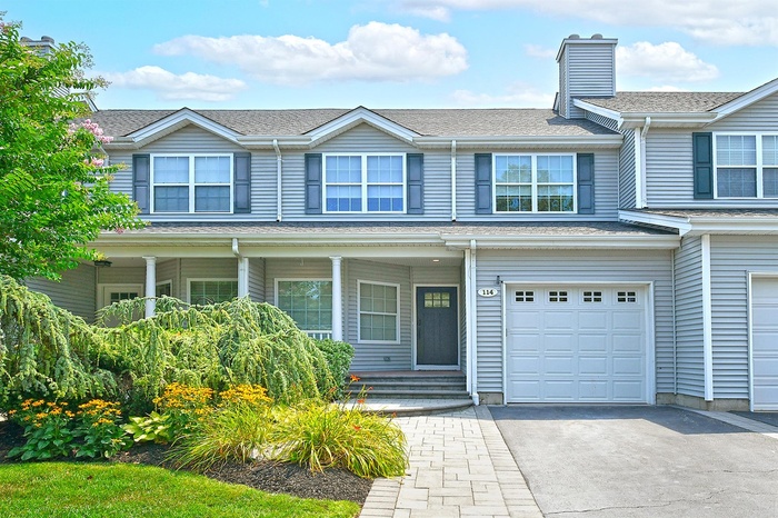 Traditional-style house featuring driveway, an attached garage, roof with shingles, and a porch