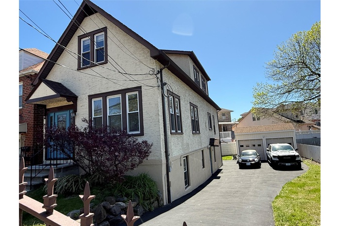 View of home's exterior with a garage, fence, a wall mounted air conditioner, stucco siding, and an outbuilding