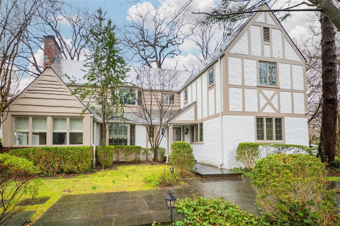English style home featuring stucco siding, a chimney, and a front lawn