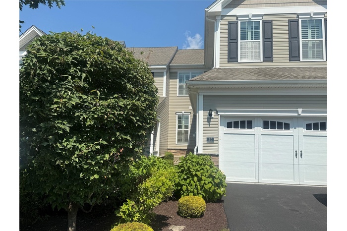 View of front of home with an attached garage, a shingled roof, and driveway