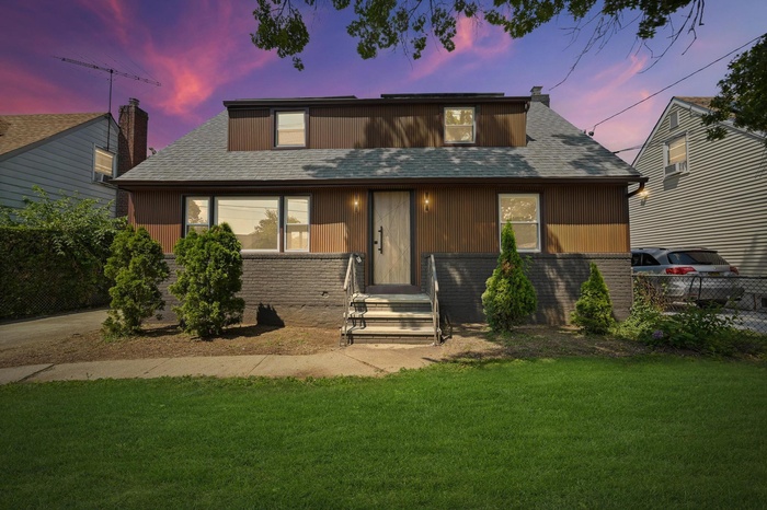 View of front of house with brick siding, roof with shingles, and a chimney