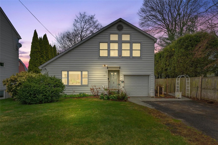 View of front of house with driveway, an attached garage, fence, and a front yard