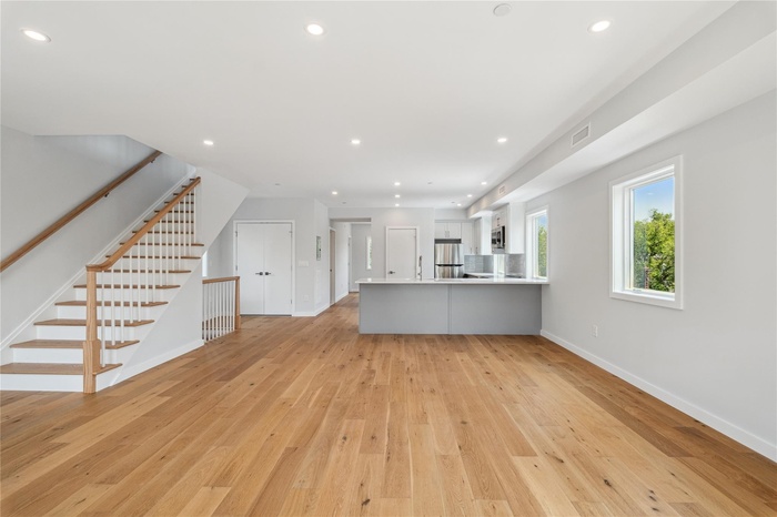 Unfurnished living room with light wood-type flooring, recessed lighting, and stairs