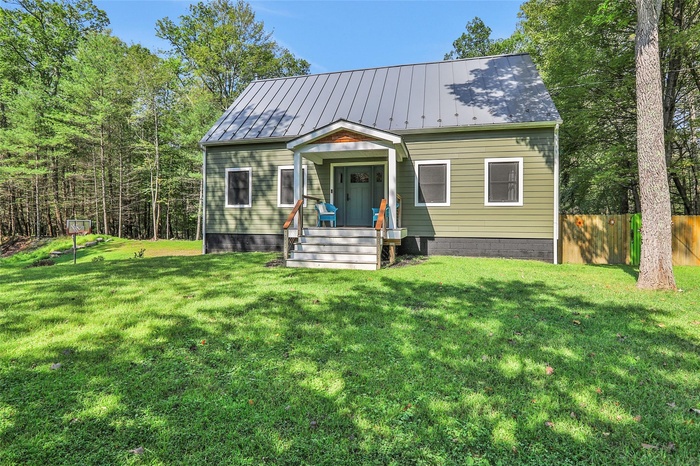 View of front of home with metal roof, a front lawn, a standing seam roof, and fence