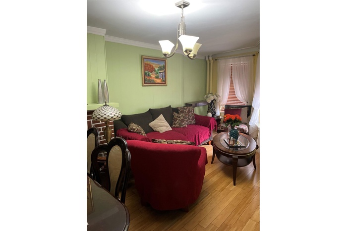 Living area featuring wood finished floors, a chandelier, and crown molding