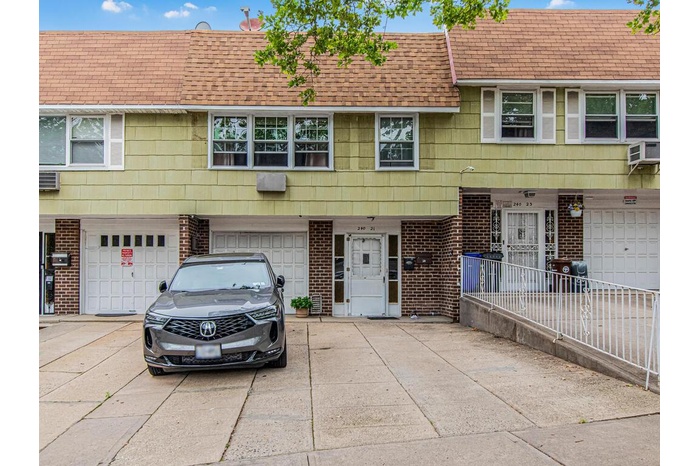 Townhome / multi-family property with a shingled roof, brick siding, driveway, and an attached garage