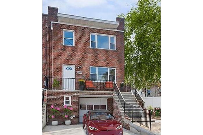 Traditional home featuring brick siding, a garage, driveway, and stairway