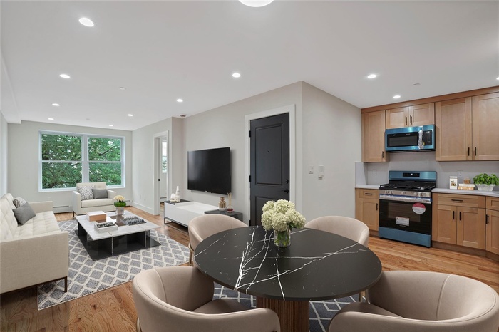 Living room featuring light wood finished floors, recessed lighting, and a baseboard heating unit