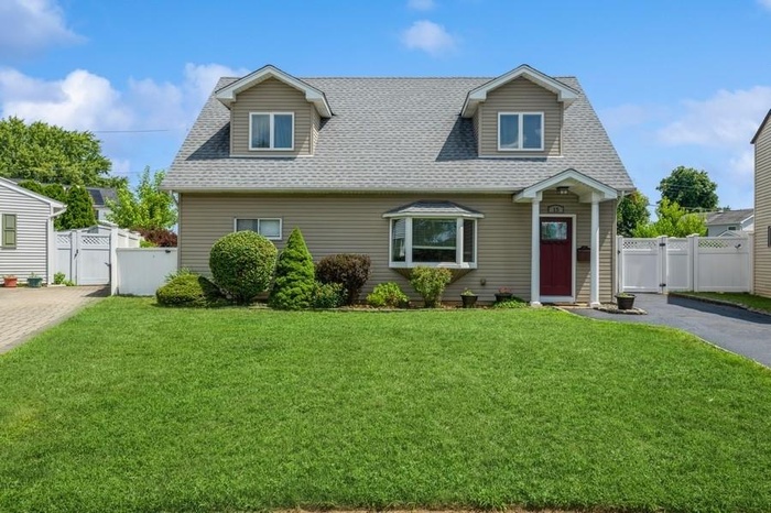 New england style home with a gate, roof with shingles, and driveway