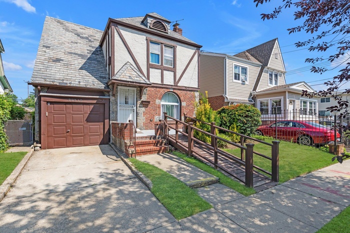 Tudor home with brick siding, a high end roof, concrete driveway, an attached garage, and a chimney