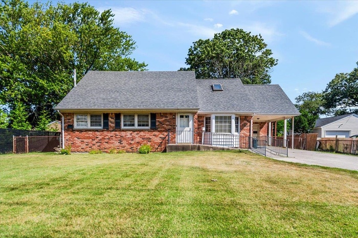 View of front of home featuring concrete driveway, brick siding, a carport, and roof with shingles