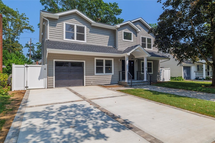 Traditional home with concrete driveway, an attached garage, roof with shingles, and a gate
