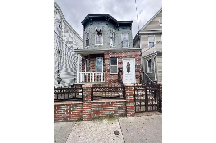 Italianate home with a fenced front yard, brick siding, a porch, and a gate
