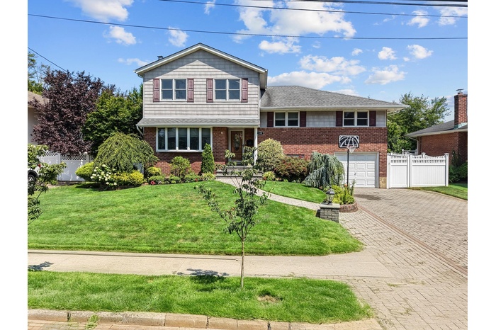 Tri-level home with decorative driveway, an attached garage, and brick siding