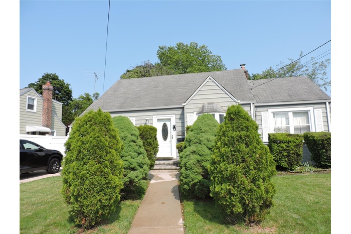 View of front facade with a front yard, roof with shingles, and entry steps