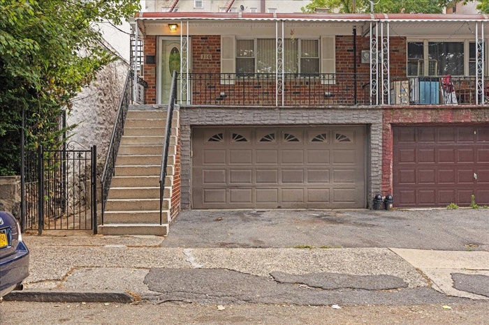 View of front facade featuring brick siding, stairs, an attached garage, and asphalt driveway