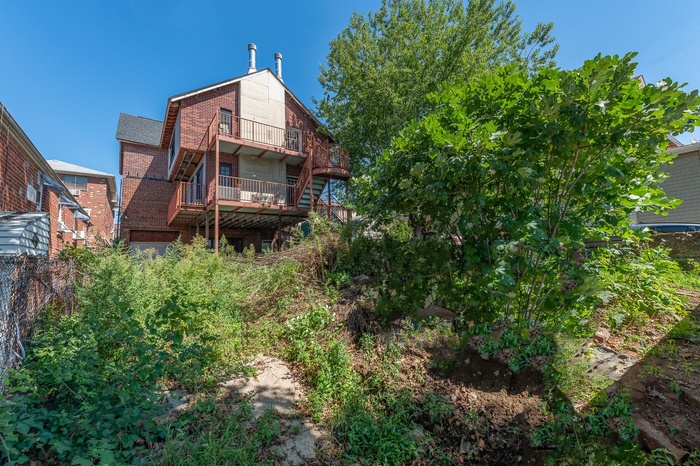 Back of house with a balcony, brick siding, and a wooden deck