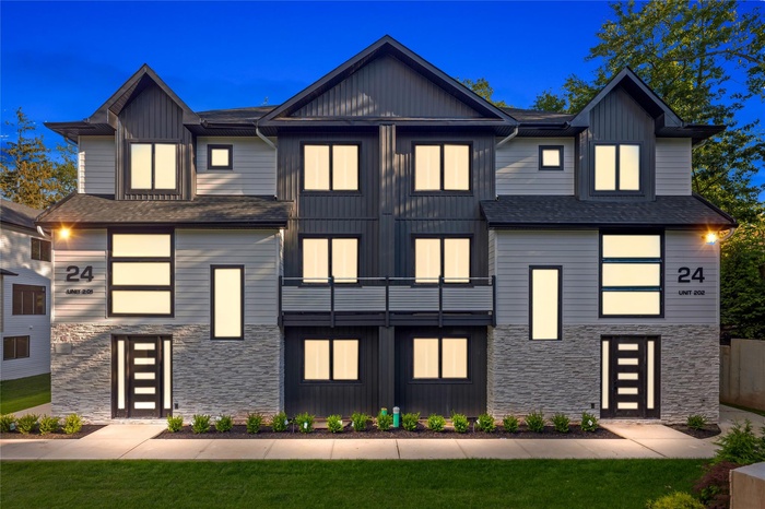 View of front of property featuring stone siding, a balcony, board and batten siding, and roof with shingles