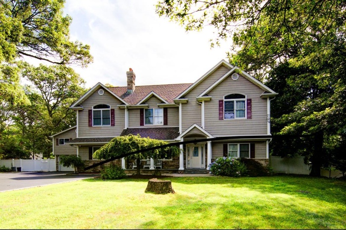 View of front of house with a chimney and driveway