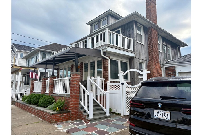 View of front of house featuring a balcony, a chimney, and brick siding