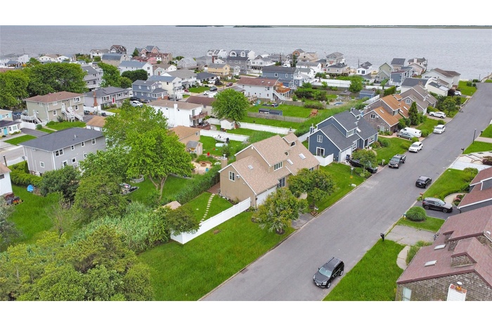 Aerial view of property and surrounding area featuring nearby suburban area and a large body of water