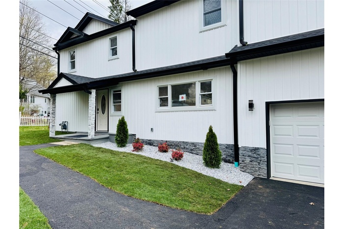 Modern farmhouse featuring fence, a front yard, and a garage