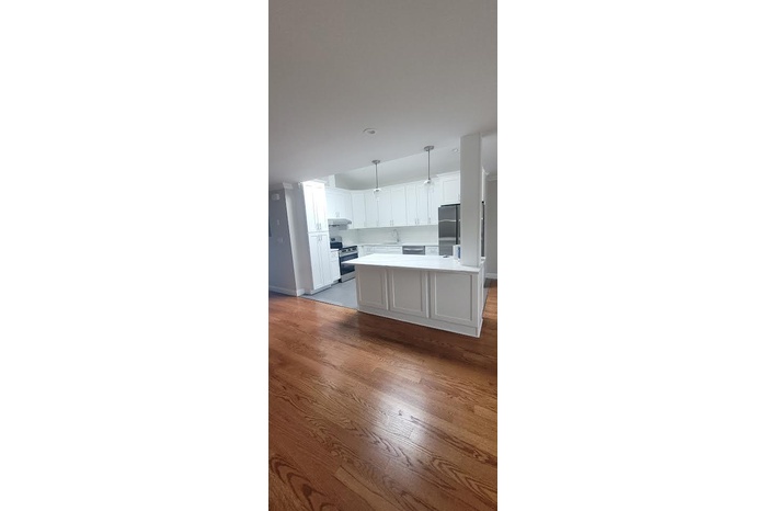 Kitchen with white cabinets, stainless steel appliances, pendant lighting, and light countertops