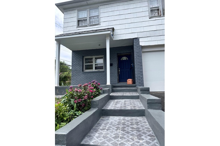 Entrance to property with covered porch and brick siding