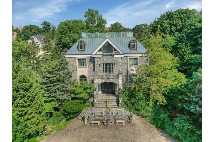 View of front of property featuring stone siding, a balcony, french doors, and a metal roof