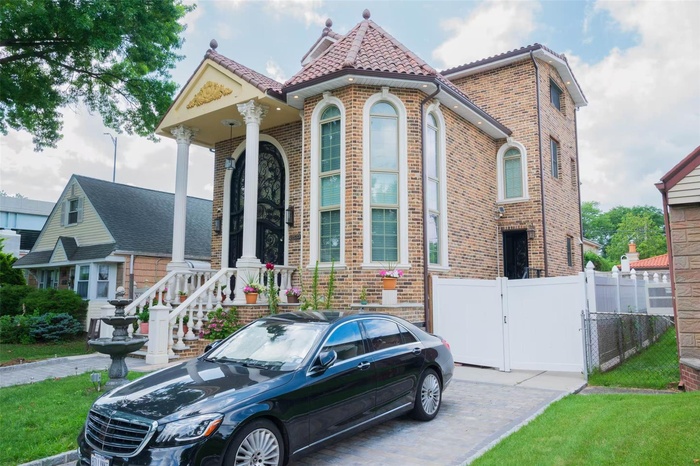 View of front facade featuring brick siding, a tile roof, and a gate